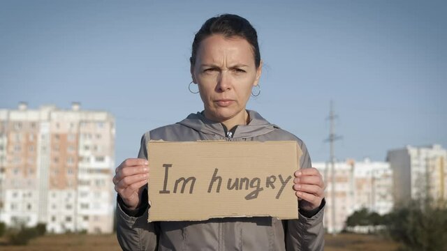 Stay without job. A view of a woman in medical mask asked for a job with a cardboard in the street. A concept of workless time during epidemic.