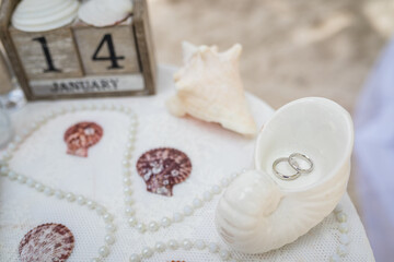 Close up view of wedding rings in the white ceramic shell on the table with wedding decor at the beach wedding ceremony, Punta Cana, Dominican Republic