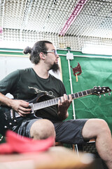 Obraz premium Guitarist playing guitar while sitting on the chair.