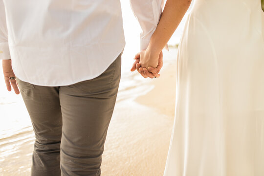 Close up view of couple bride and groom holding each other's hands and walking at the paradise beach, Punta Cana, Dominican Republic