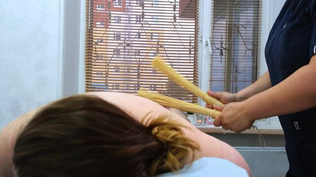 the masseur makes anti-cellulite massage of fat female legs with bamboo sticks. The therapist makes treatments to improve the condition of the skin. Aggressive fight against fat. Spa treatment.