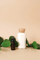 Cosmetic set of two bottles for layout packaging of cream and oil for skin care on a beige background with green leaves. The concept of an organic product of natural beauty.