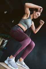 Best calorie burning Exercises. Bottom view of a strong athletic woman in sportswear doing box jump...