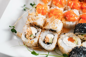 Top view of assorted sushi rolls on white plate close-up. Japanese food.