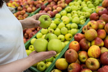 Woman's hand choosing green apple in the supermarket. Healthy,natural food