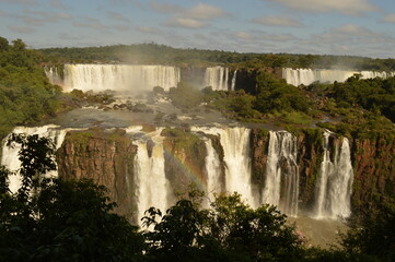Fototapeta premium A rainbow over the huge Iguazu River and Waterfalls in Brazil and Argentina
