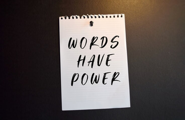 Paper note with WORDS HAVE POWER written on black slate board