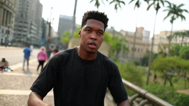 Young black man shaking head in downtown street dancing to beat song