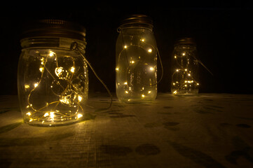LED lamps in jars on garden table at night