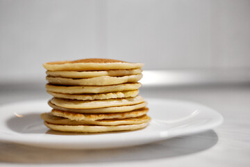 A stack of pancakes is on a white plate