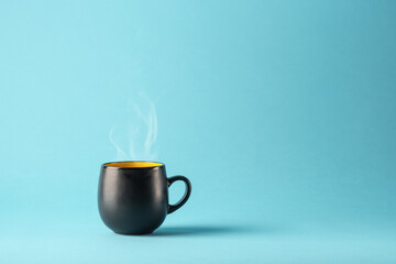 Black and yellow matte ceramic mug casting a shadow on a bright blue background