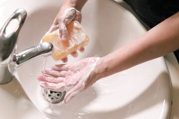 manos lavandose con una pastilla de jabon en un lavabo