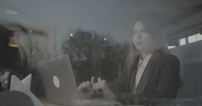 A successful business woman is sitting and working on a laptop computer in cafe, typing text. She looks thoughtfully out the window. Suddenly finds a desicion. Prores 4444. 4k.