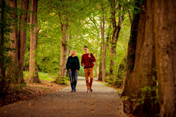 Fototapeta premium Beautiful woman,blonde,middle-aged,walking with her big son , autumn in the Park,Sunny day.
