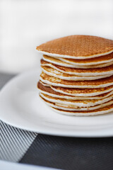 A stack of pancakes is on a white plate