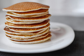 A stack of pancakes is on a white plate