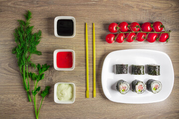 Sushi set is served on a plate, Board on the background. Traditional Japanese cuisine, sushi rolls close-up. Top view of assorted sushi rolls on white plate close-up.