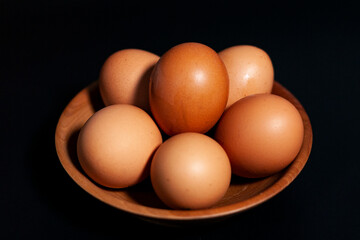 Chicken eggs in a Cup in the lower left corner of the frame. On dark background.