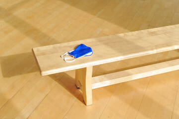 Blue protective mask on a bench in a physical education lesson. Safe back to school during pandemic concept