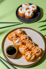 Rolls with shrimps and spicy sauce on green background