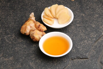 Honey in bowl and a slices ginger root.