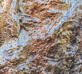 A relief stone, painted in dark yellow, dark green, dark red. Can be used as a background.