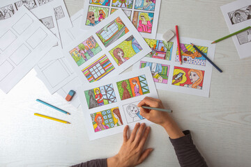 An animator painter draws a color storyboard for a comic book or movie. An illustrator seated at his desk creates a storyboard for a cartoon. - 382232725