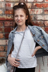 portrait of a beautiful teenage girl posing against a brick wall