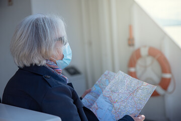 Senior tourist woman with face mask and map
