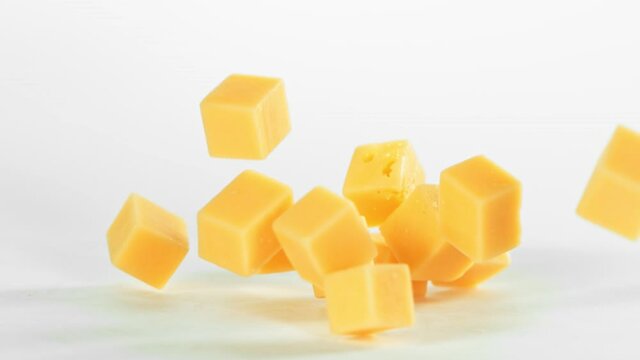 Super Slow Motion Shot of Cheese Chunks Falling on White Background at 1000 fps.