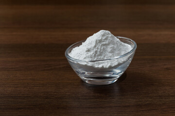 Baking soda (sodium bicarbonate) on dark wooden background.