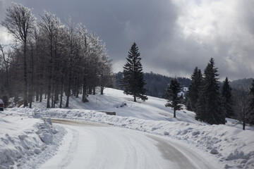 Obraz premium Roadtrip durch Rumänien, einsame verschneite Straßenkurve im Gebirge