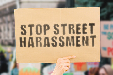 The phrase " Stop street harassment " on a banner in men's hand with blurred background. Outdoor. Crime. Violation. Illegal. Dangerous. Stranger. Scary
