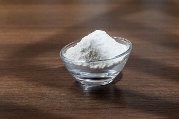 Baking soda (sodium bicarbonate) on dark wooden background.