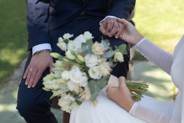bride in white suit holds pretty bouquets of flowers with her groom