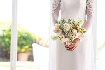 bride in white suit holds pretty bouquets of flowers