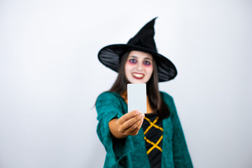 Woman wearing witch costume over isolated white background smiling and holding white card