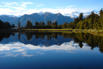 Fototapeta na wymiar Mirrored lake with snow capped mountains in New Zealand, luxury travel, adventure, wild travel, great outdoors, grasslands, wetlands