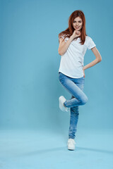 Pretty woman in white t-shirt blue jeans lifestyle in full growth studio blue background