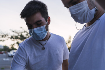 Caucasian friends with medical masks trying to fix the car on the road - new normal after Covid-19