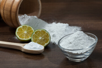 Baking soda - sodium bicarbonate and lemon; on dark wooden background.