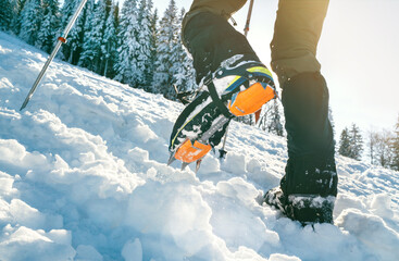 Close up shot of mountain boots with crampons and snow gaiters with backlight sun beams and snowy...