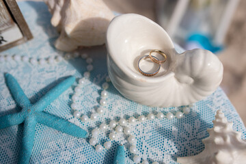 Close up view of wedding rings in the white ceramic shell on the table with wedding decor at the beach wedding ceremony, Punta Cana, Dominican Republic