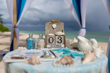 Close up view of table for the beach wedding ceremony with decoration of shells, jars with color sand, wooden calendar inside bamboo gazebo, Punta Cana, Dominican Republic