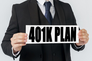 A businessman holds a sign in his hands which says 401K PLAN