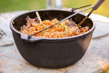 Preparation of raditional armenian pilaf in a cauldron on an open fire.