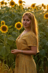 Beautiful young woman in a field of sunflowers in a yellow dress
