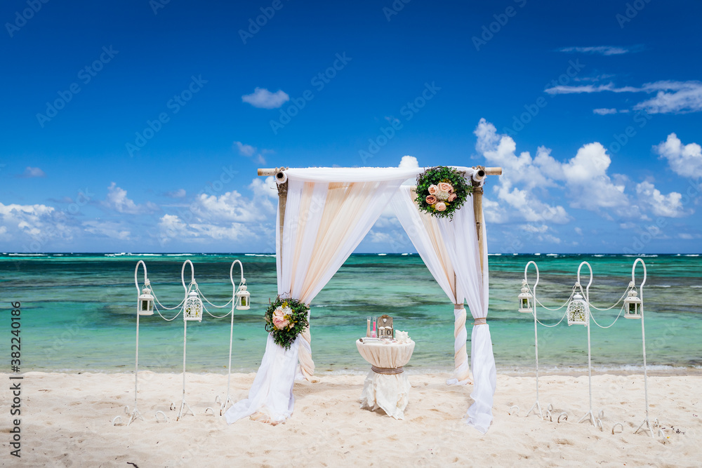 Wall mural Wedding bamboo gazebo, decorated with tropical flowers and coloured fabrics on the paradise beach with palm trees, white sand and blue water of Caribbean Sea, Punta Cana, Dominican Republic