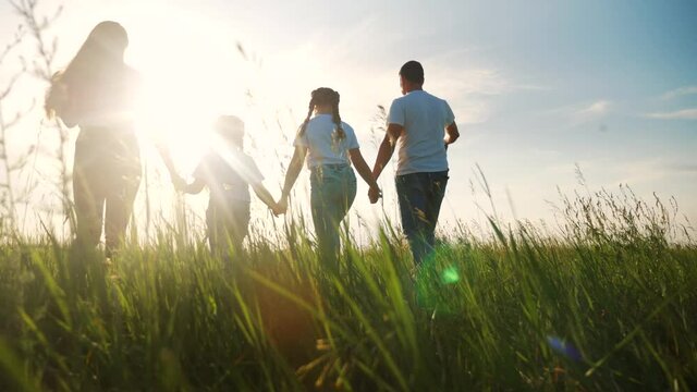 happy family walking together in the park silhouette. friendly family kid dream concept. happy family walking holding hands in the park on the grass at sunset. friendly family dream lifestyle together