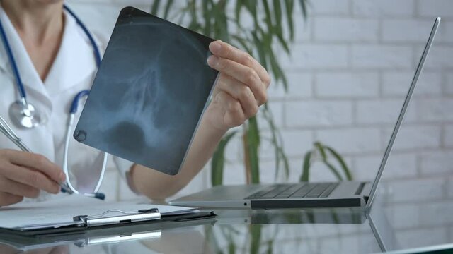 Doctor with internet device. A doctor woman describes the results of an x ray image and writes it on paper in the cabinet.